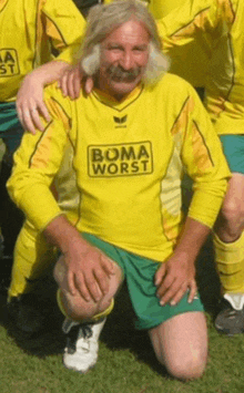 a man with a mustache is wearing a yellow shirt that says boma worst