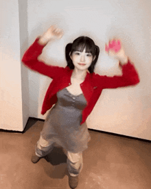 a girl in a red cardigan and a gray dress is dancing .