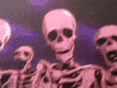 a group of pink skeletons are dancing together on a stage .