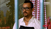 a man wearing glasses and a necklace is on astro citra