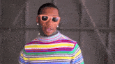 a man wearing a striped shirt and sunglasses looks down