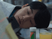 a man is laying down with a book and a glass of orange juice in front of him