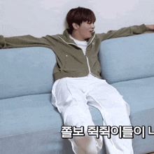 a man is sitting on a blue couch with his arms outstretched in korean