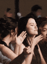 a woman in a black dress is clapping her hands together
