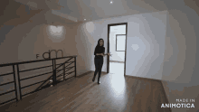 a woman stands in an empty room with the words made in animatica on the bottom right