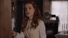 a woman with red hair is standing in front of a shelf