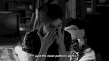a black and white photo of a woman covering her face with her hands and the words " i 'm just the most pathetic person "