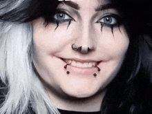 a close up of a woman 's face with black and white hair and piercings .