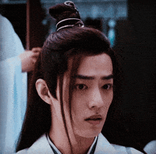 a man with long hair and a bun on his head