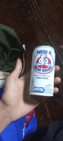 a person holding a can of nestle bear brand milk