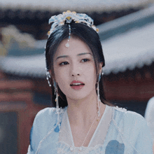 a close up of a woman wearing a blue dress and pearls