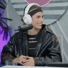 a woman wearing headphones and a headband smiles at the camera