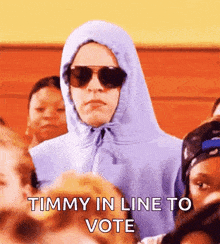 a man wearing a hoodie and sunglasses is standing in a crowd and says timmy in line to vote .