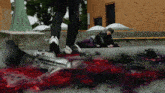 a person standing next to a person laying on the ground covered in blood