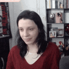 a woman in a red sweater stands in front of a shelf with a poster that says the red velvet