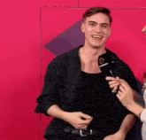 a man in a striped shirt is holding a microphone with a triangle on it and smiling