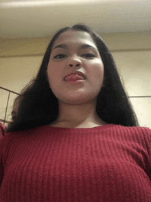 a woman in a red sweater is sticking out her tongue
