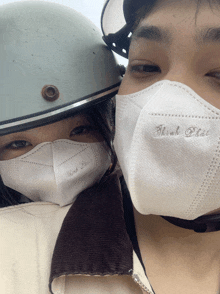 a man and a woman wearing face masks with the word tinh that embroidered on them