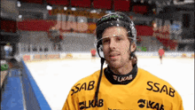 a man wearing a helmet and a yellow shirt with ssab written on it