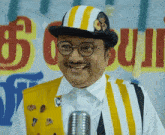 a man wearing a hat and glasses is smiling in front of a sign that says ' g ' on it