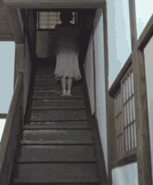 a woman in a white dress is walking down stairs