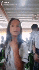 a girl in a school uniform is standing in a classroom with a group of people .