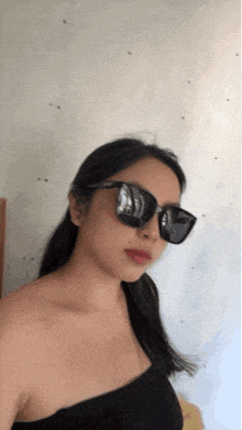 a woman wearing black sunglasses and a black top