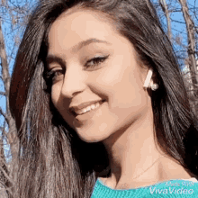 a close up of a woman 's face wearing a blue sweater and earrings and smiling .