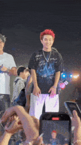 a man with red hair is standing on a stage with a phone in front of him
