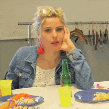 a woman sits at a table with plates of food and a green bottle with the word california on it