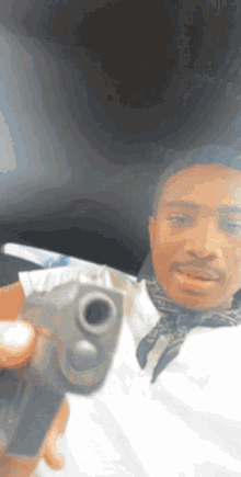 a man in a bandana holds a gun in front of his face