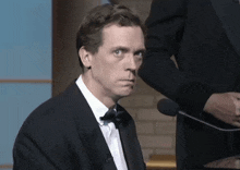 a man in a tuxedo with a bow tie looks at the camera