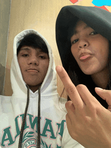 a man and a woman are posing for a picture and one of them is wearing a hoodie that says ainay