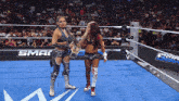 two women are standing in a wrestling ring with the word sma on the wall behind them