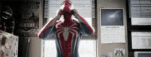 a man in a spider man costume is standing in front of a window .
