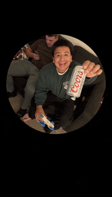 a man is holding a can of coors light in his hand