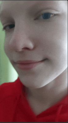 a close up of a young girl 's face with a red shirt on