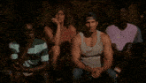 a man in a tank top and hat is standing next to another man in a pink shirt .