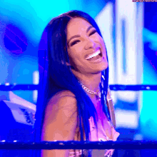 a woman with long blue hair is laughing in a ring .