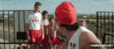 a man wearing a lifeguard shirt stands next to a group of boys