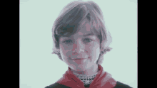 a young girl wearing a red scarf and a black shirt is smiling for the camera .