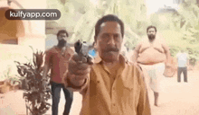 a man with a mustache is pointing a gun at someone .