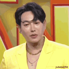 a man wearing a yellow jacket and a gold necklace with a cross pendant