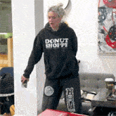 a woman wearing a black donut shoppe hoodie