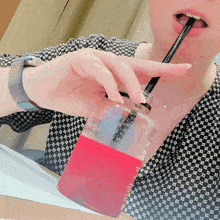 a woman drinking from a bottle with a straw that says ' strawberry ' on it