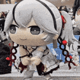 a stuffed doll with white hair and red ribbons in her hair is standing on a sidewalk