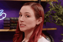 a woman with red hair is making a funny face in front of a neon sign that says xxiv