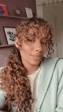 a woman with curly hair is wearing a light blue sweater