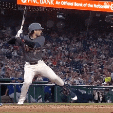 a baseball player swings his bat in front of a sign that says pnc bank an official bank of the nationals