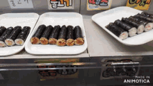 several trays of sushi are lined up on a counter with a sign that says made in animotica on it